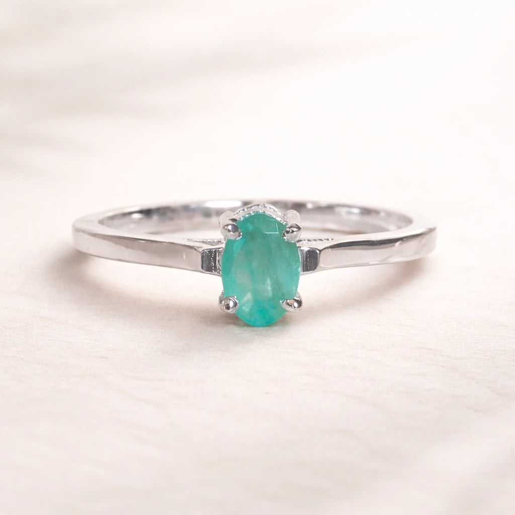 Sterling Silver ring with a oval solitaire claw set natural emerald gemstone on a light background