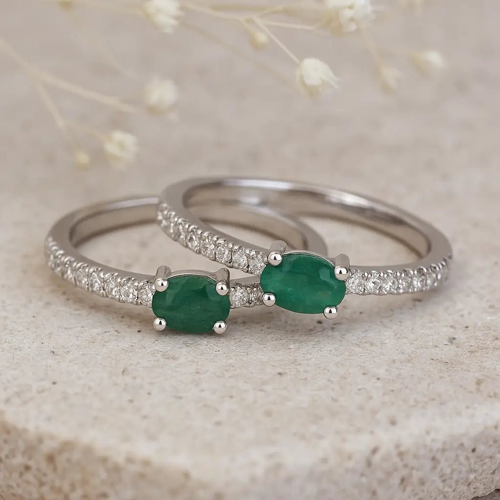 Silver rings with green emerald gemstones on a textured surface