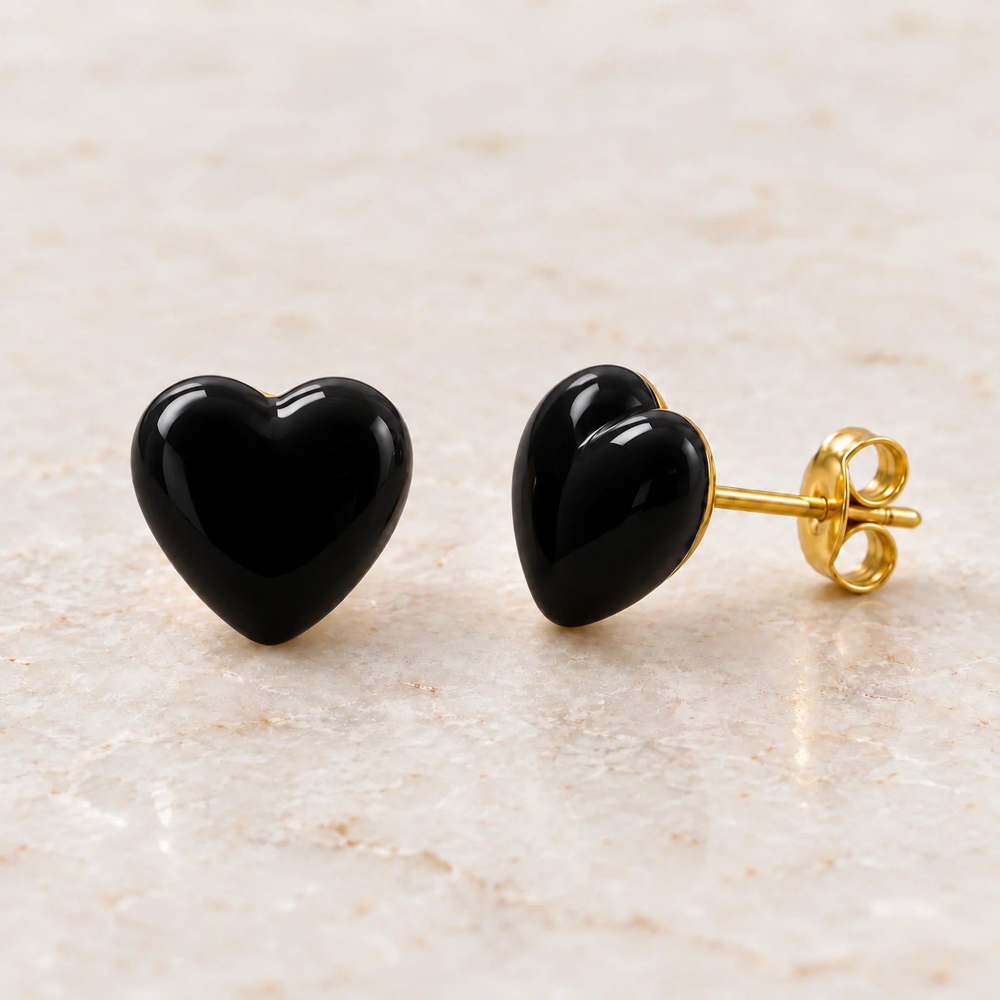 Black epoxy heart stud earrings in gold PVD stainless steel, angle view