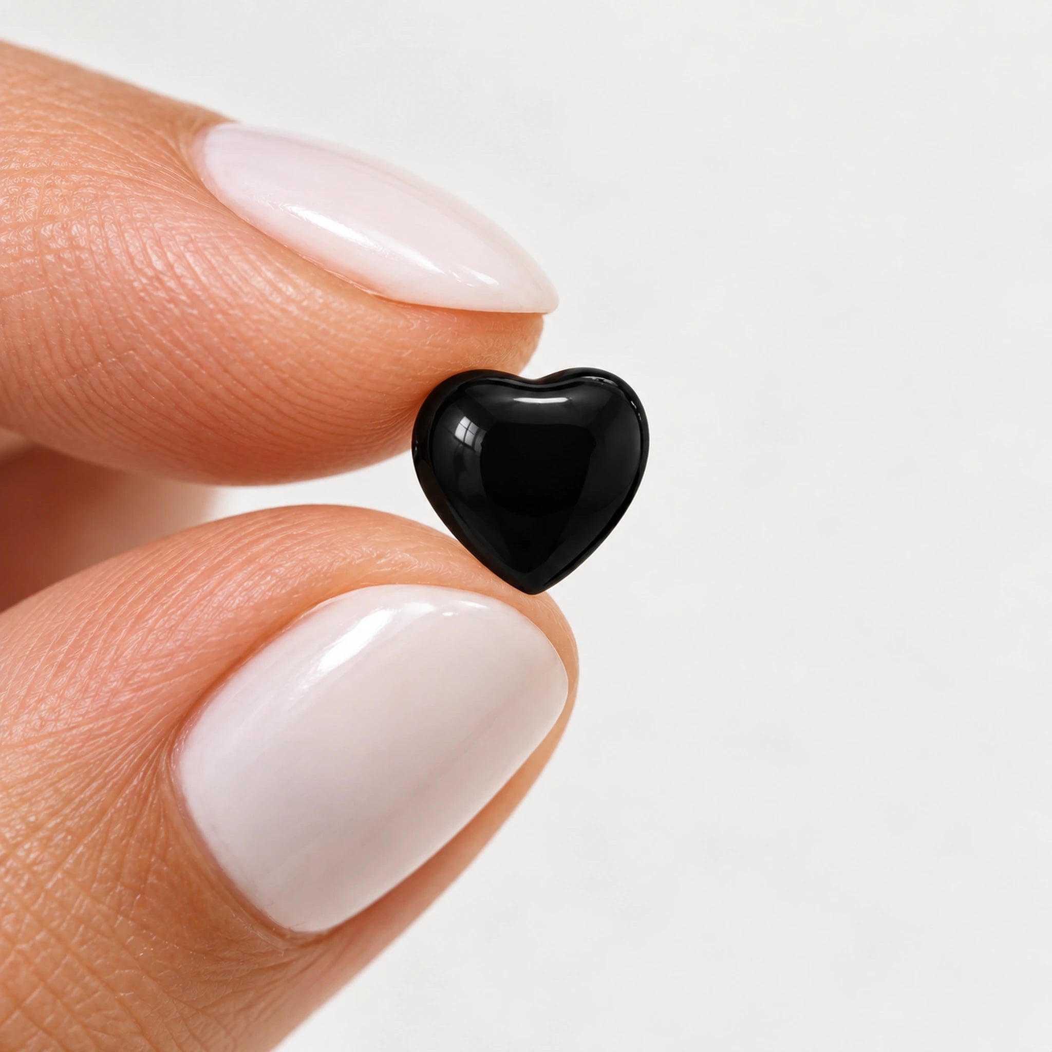 Black epoxy heart stud earrings in gold PVD stainless steel, held view