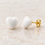 White epoxy heart stud earrings in gold PVD stainless steel, angle view