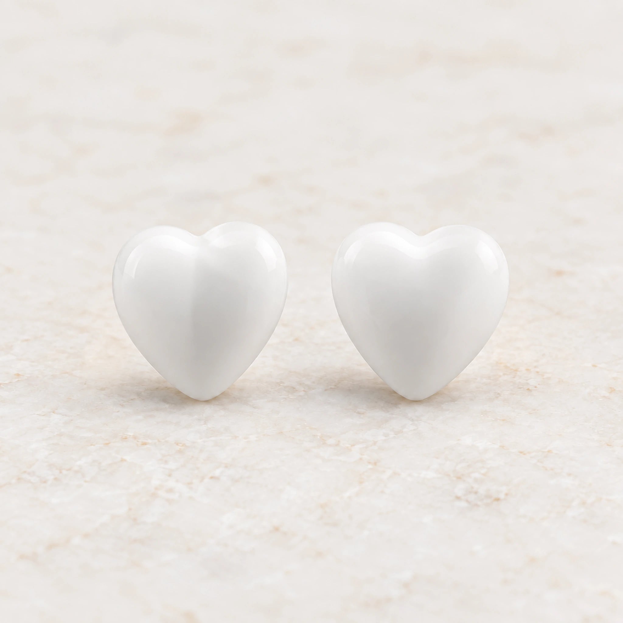 White epoxy heart stud earrings in gold PVD stainless steel, front view