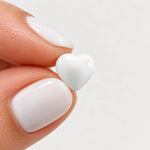 White epoxy heart stud earrings in gold PVD stainless steel, held view