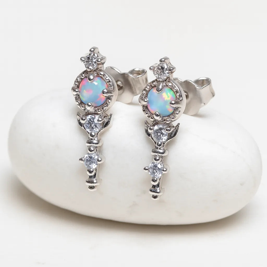 Silver earrings with opal stones on a white stone surface