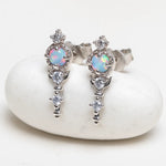 Silver earrings with opal stones on a white stone surface