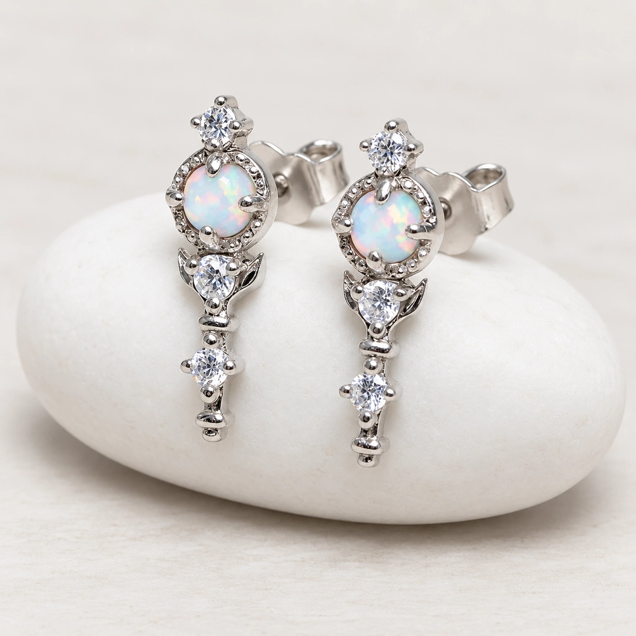 Silver earrings with opal stones on a white stone surface