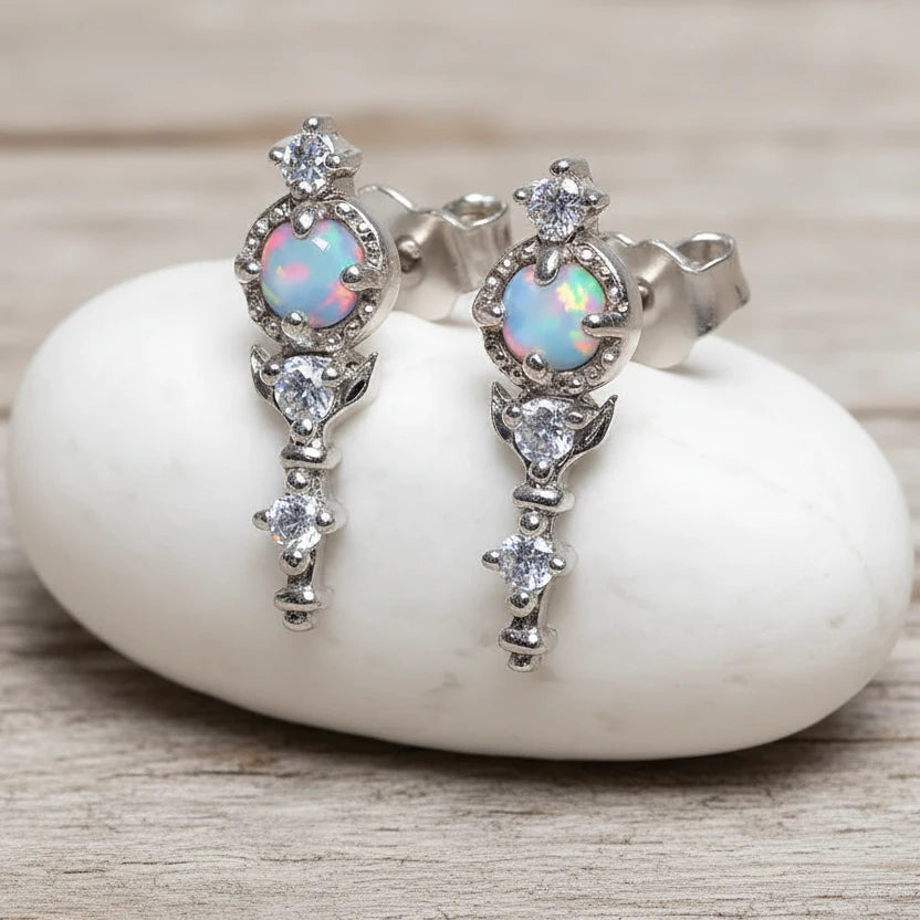 Silver earrings with opal stones on a white stone surface