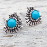 Silver earrings with turquoise stones on a wooden surface