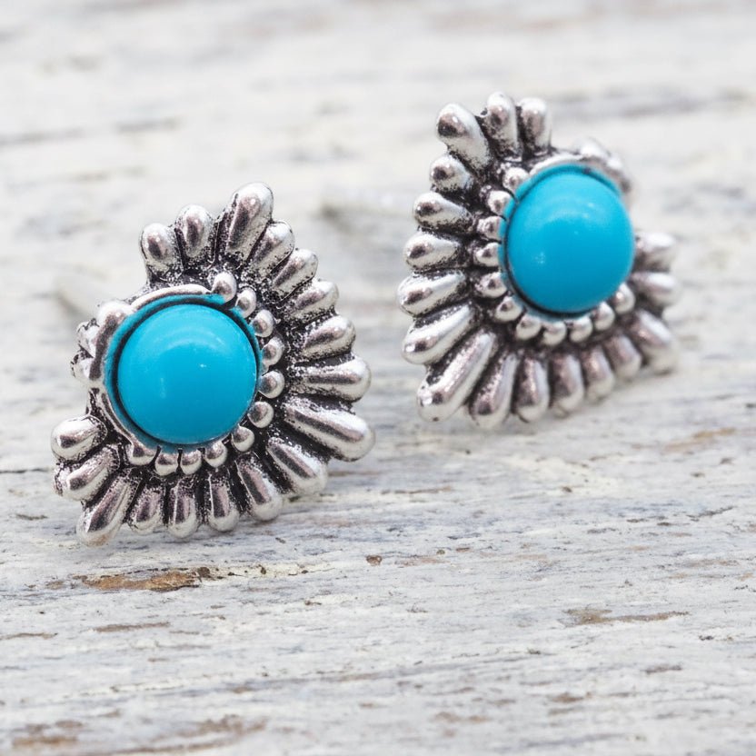 Silver earrings with turquoise stones on a wooden surface