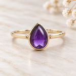 Soft 9k gold February birthstone ring with natural pear-shaped amethyst on ivory stone