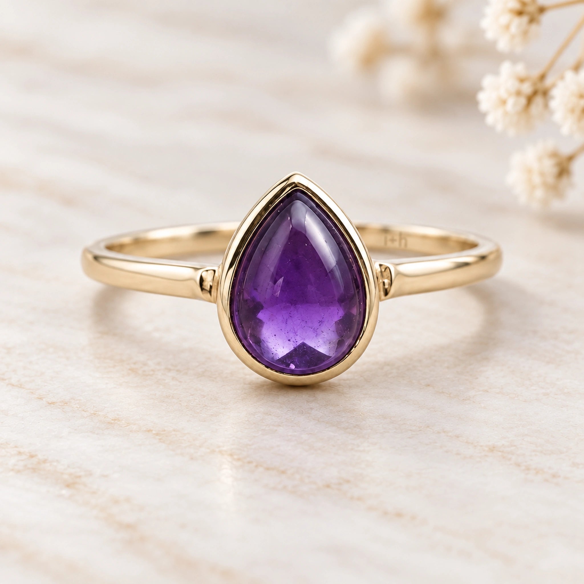 Soft 9k gold February birthstone ring with natural pear-shaped amethyst on ivory stone