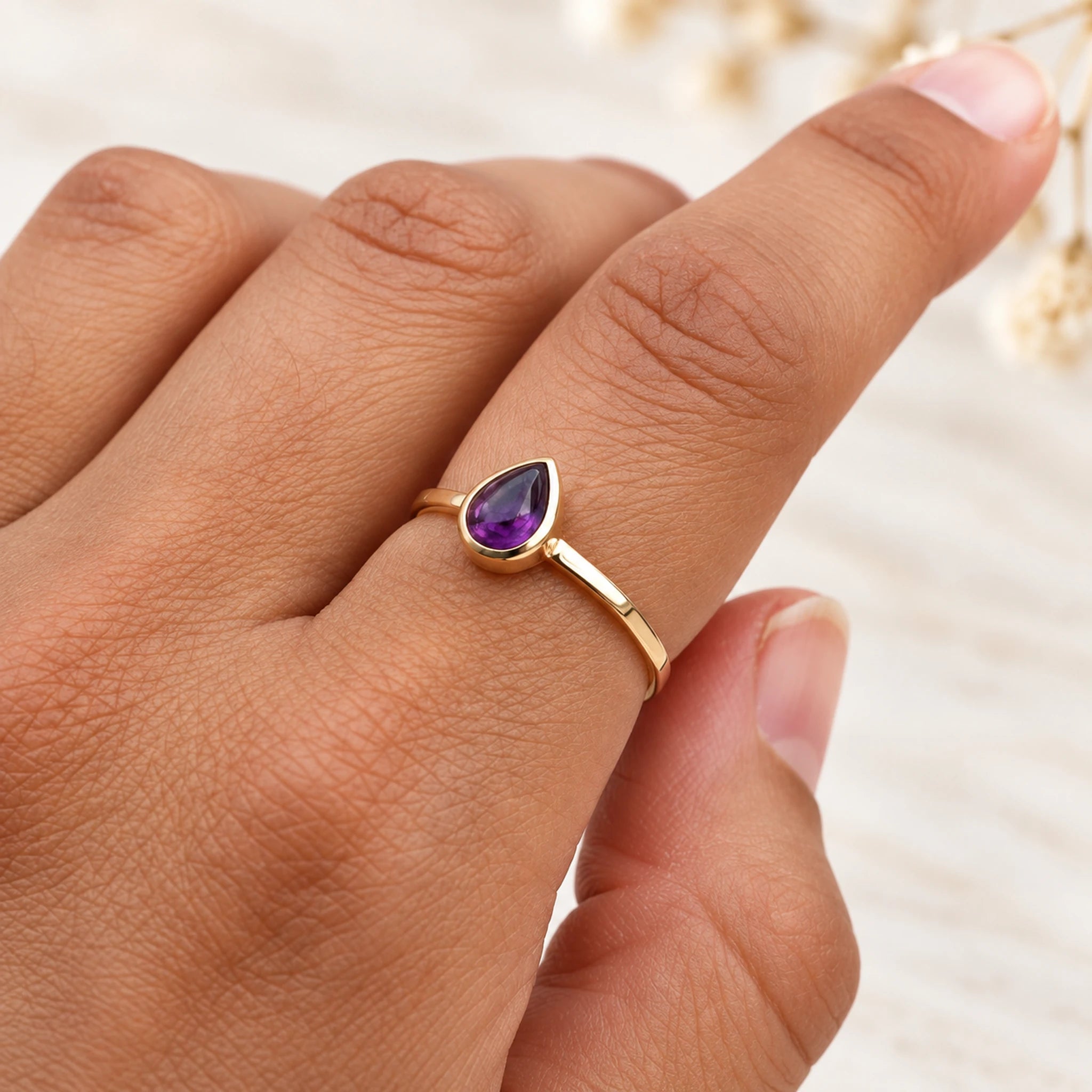 Soft 9k gold February amethyst birthstone ring worn on a hand