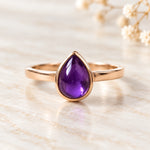 Soft 9k rose gold February natural amethyst birthstone ring on ivory stone