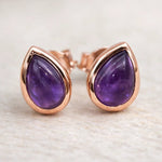 Pair of purple teardrop earrings with rose gold frames on a light background