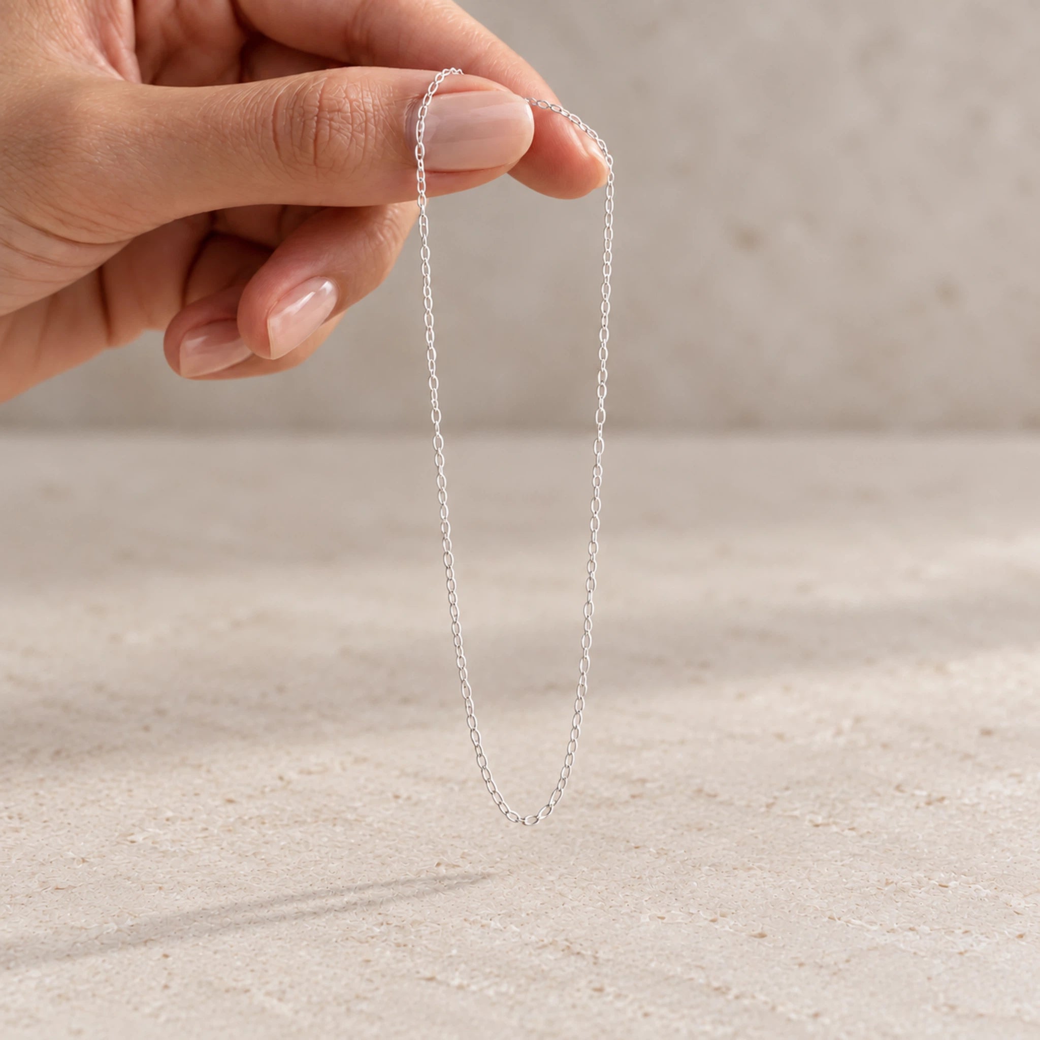 fine sterling silver cable chain necklace being held by fingers