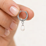 Freshwater pearl hoop earrings in silver PVD-plated stainless steel, single earring held between fingers