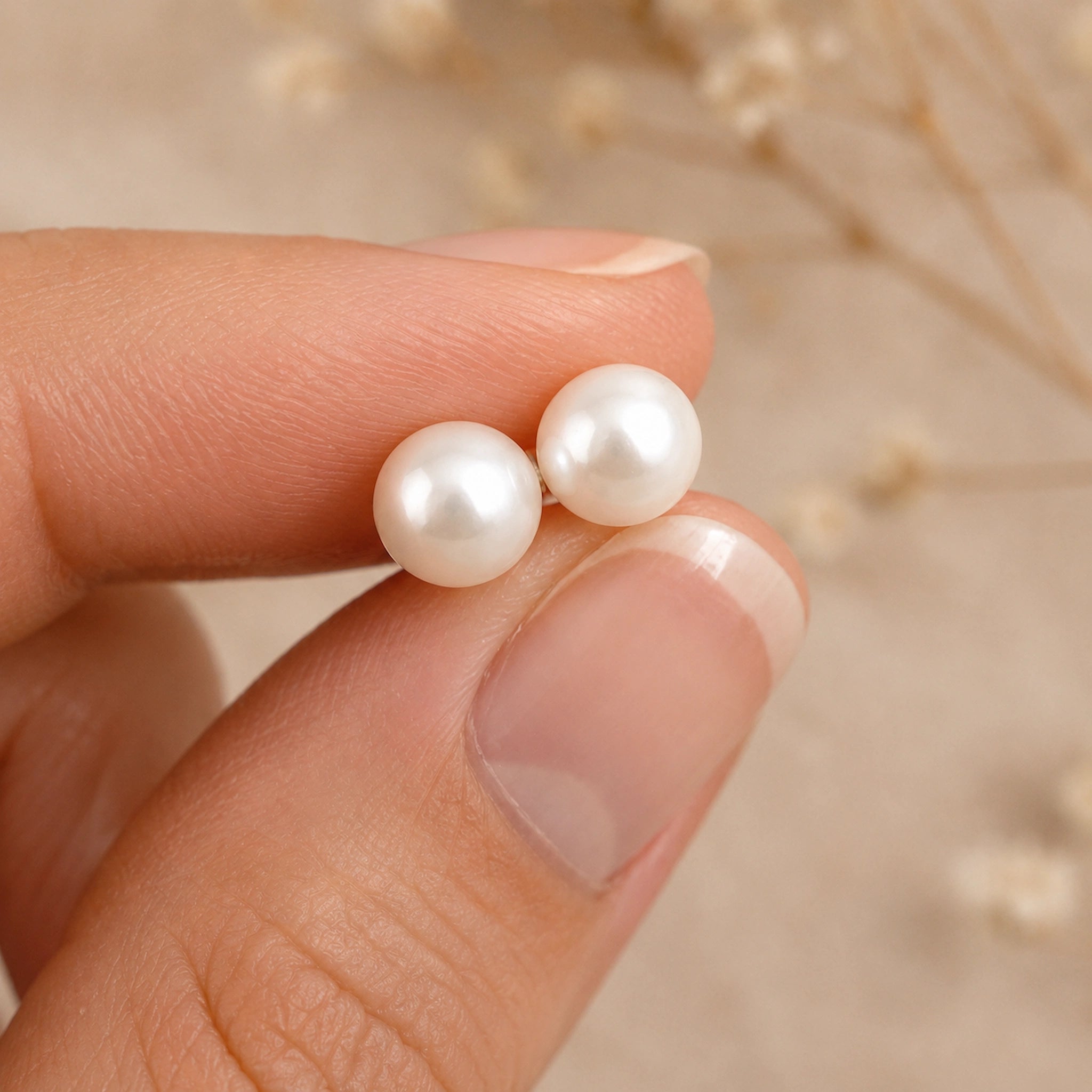 Sterling Silver Classic 7mm Natural Freshwater Pearl Stud Earrings held by fingers with a light background.