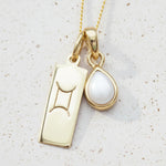 Gold gemini zodiac pendant necklace with a june birthstone pearl pendant on a light background - personalised birthday jewellery gift