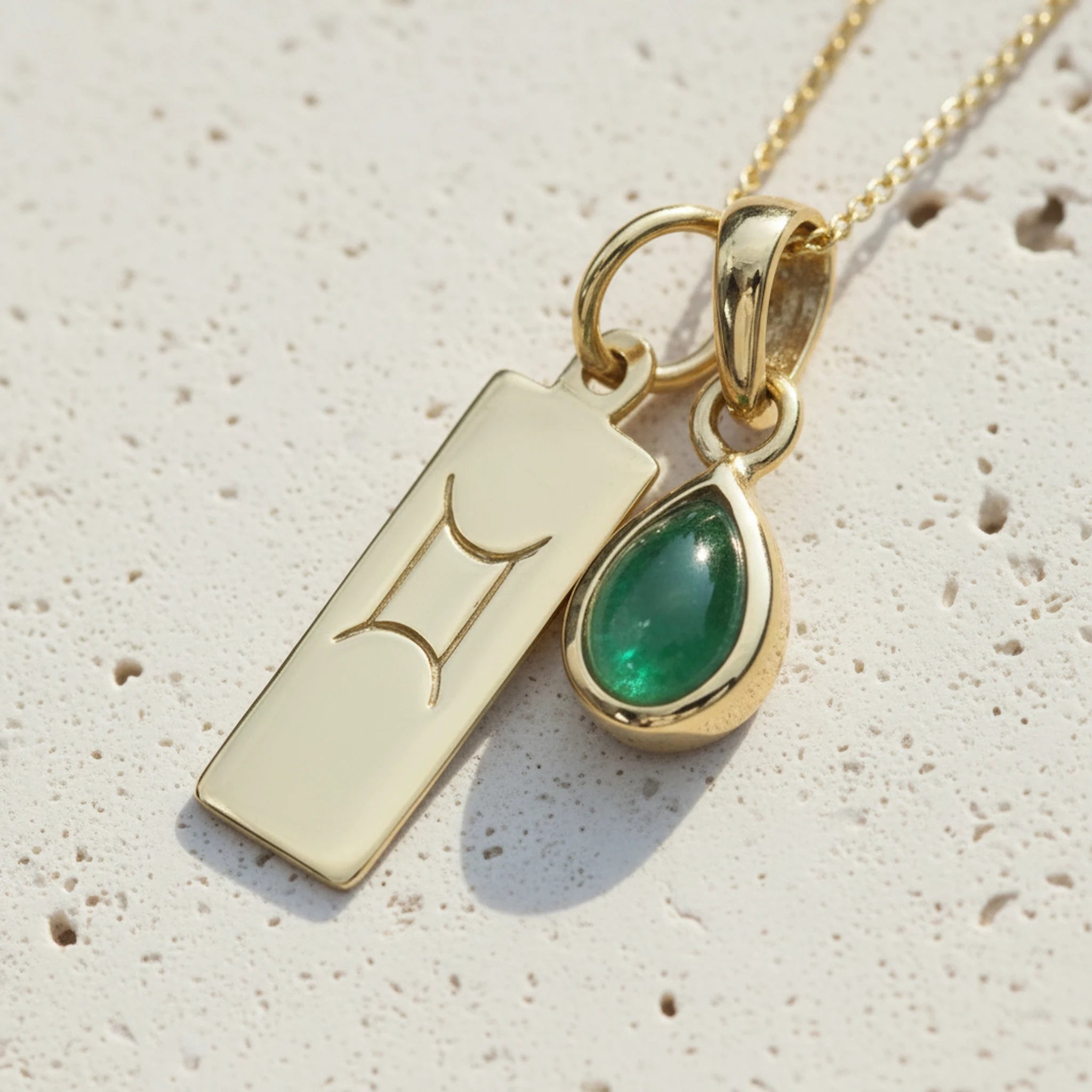 Gold May Birthstone necklace with a pear-shaped natural emerald pendant and a Gemini zodiac pendant