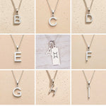 Collection of sterling silver letter pendants a, b, c, d, e, f, g, h, i on a beige background as personalised initial options for Gemini Zodiac Necklace.