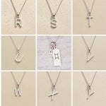 Collection of sterling silver letter pendants r to y on a beige background as personalised initial options for Gemini Zodiac Necklace.