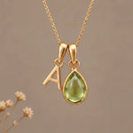 Gold Initial A Pendant and August birthstone Natural Peridot Necklace against a warm background