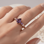 Ring with purple gemstone on a hand against a neutral background