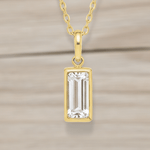 Gold pendant necklace with a rectangular clear gemstone on a white background