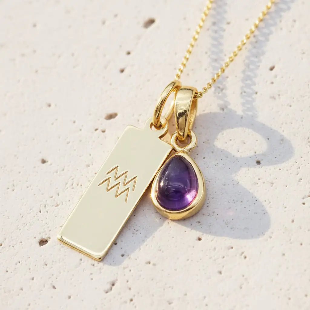 Gold Aquarius zodiac and february Birthstone amethyst Necklace on a white stone surface