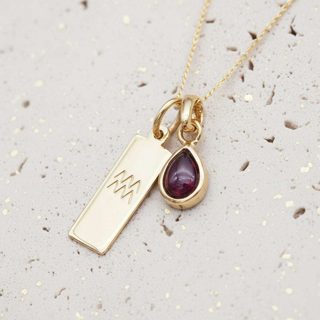 Zodiac Aquarius and January Birthstone Garnet Necklace - Gold Necklace on a light stone surface