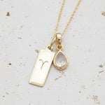 Gold necklace with Zodiac Aries pendant and april Birthstone herkimer quartz pendant on stone surface