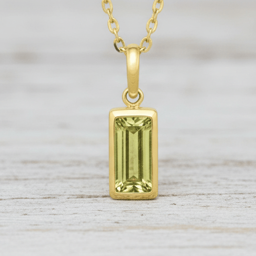 Gold pendant with a green gemstone on a white background