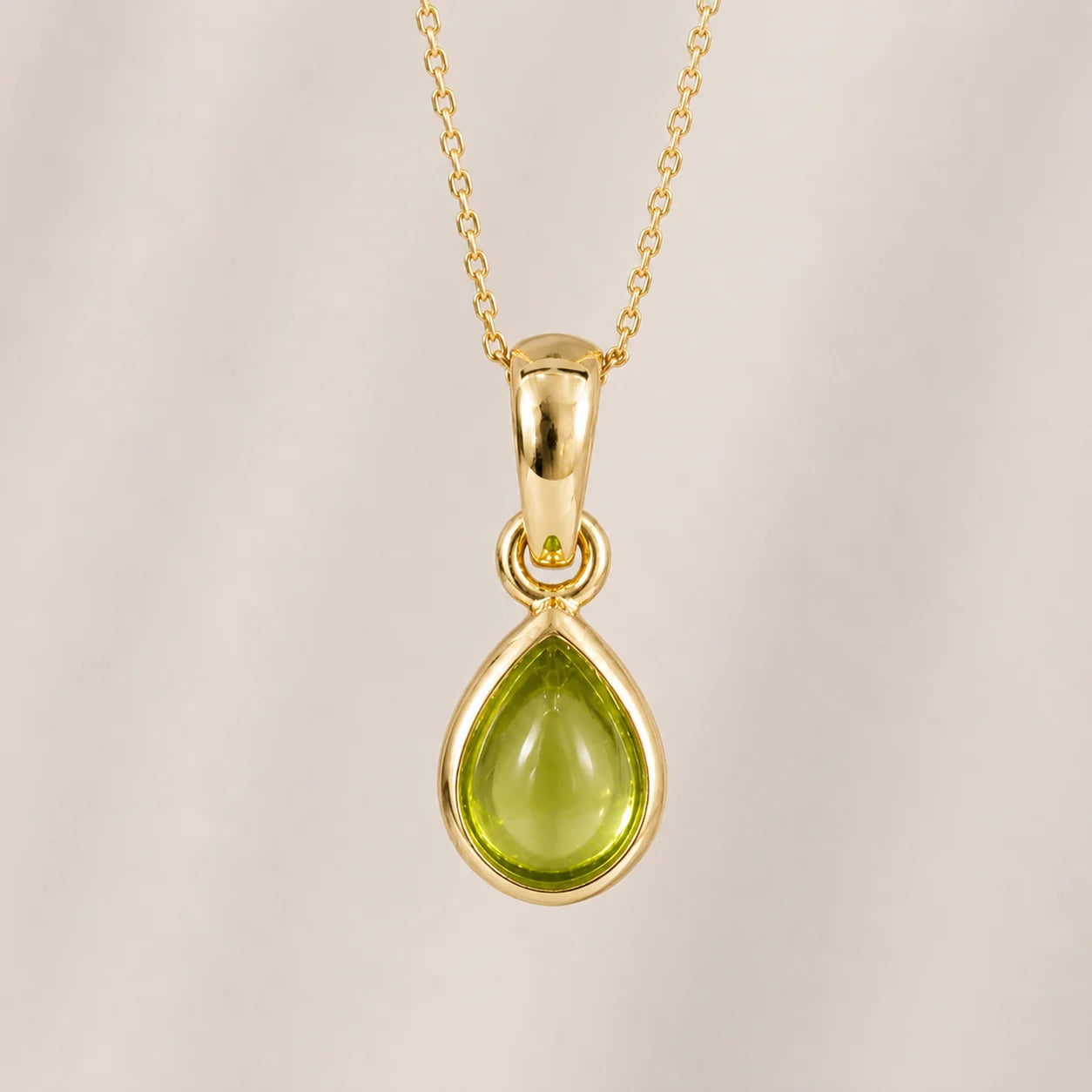 august birthstone gold teardrop pendant necklace featuring a light green natural peridot gemstone on a delicate gold chain