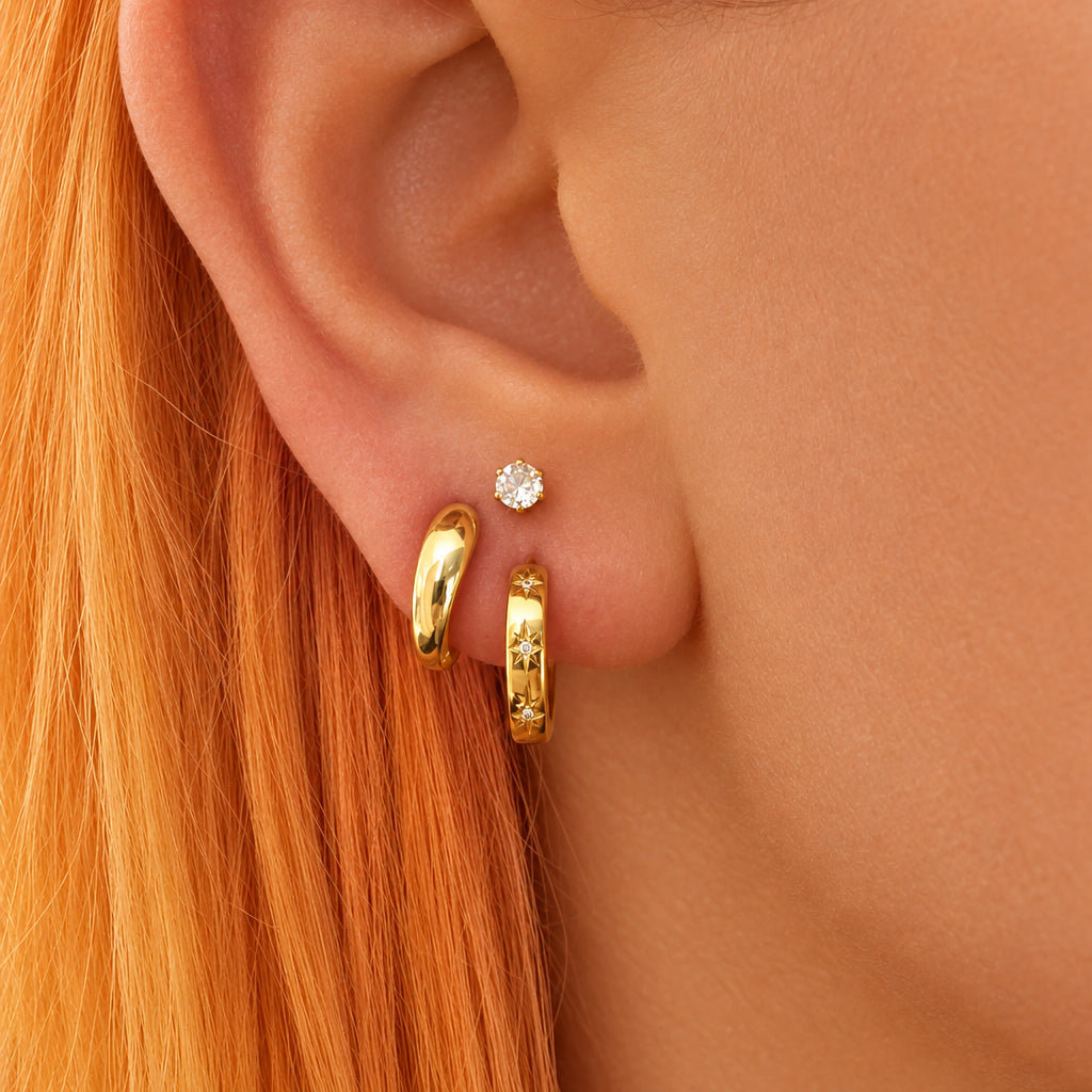 Ear stack of gold Aurora Spark star huggie hoops with a small Luna ball back stud above