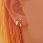 Close-up of an ear wearing gold hoop earrings with a small diamond stud