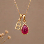 Gold Initial B Pendant and July birthstone Natural Ruby Necklace against a warm background