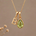 Gold Initial B Pendant and August birthstone Natural Peridot Necklace against a warm background