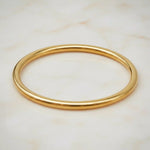 Gold bangle on a light marble background