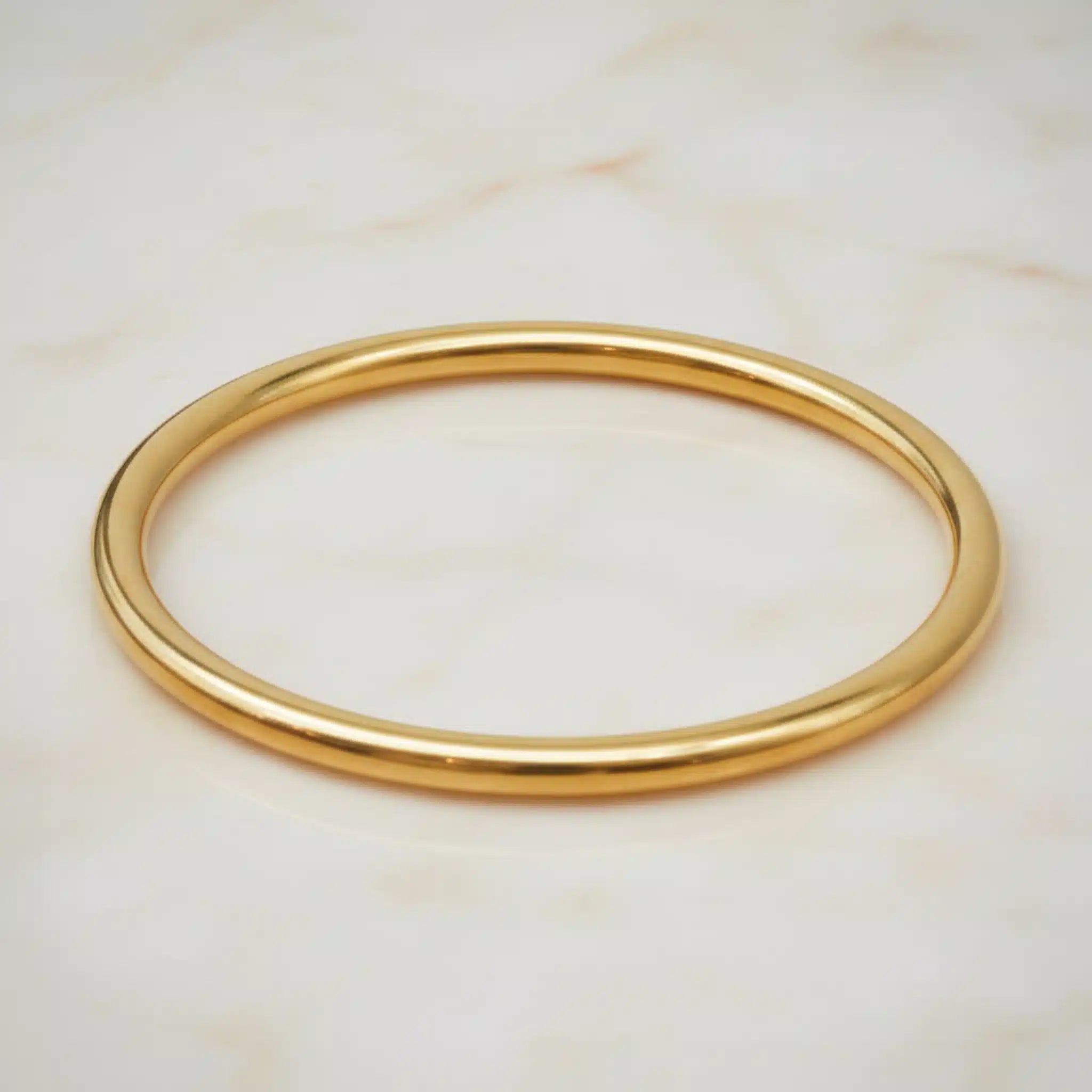 Gold bangle on a light marble background
