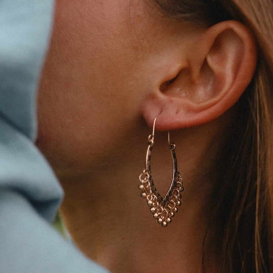 woman wearing gold dangling earring with small bead detailing