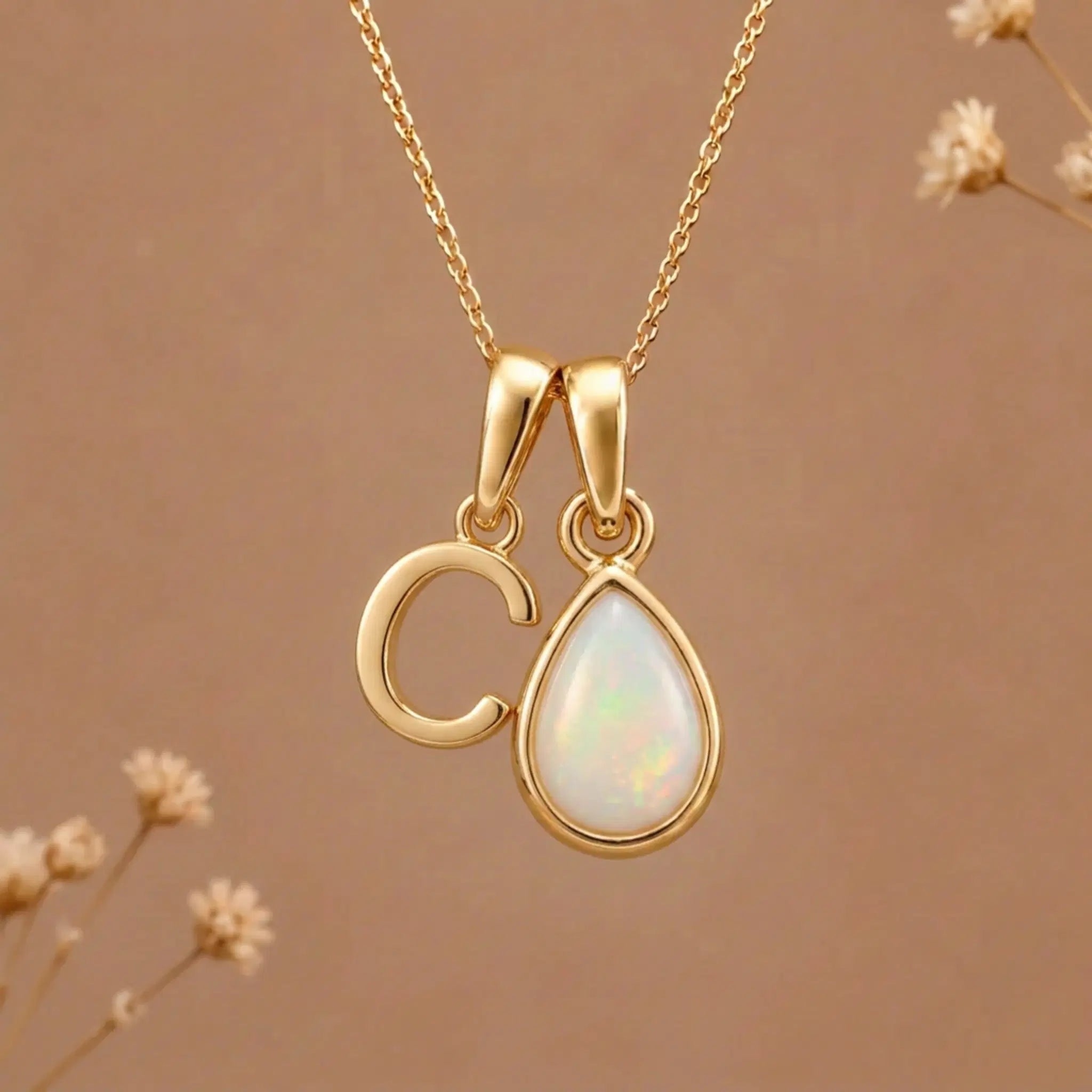 Gold Initial C Pendant and October birthstone Natural Opal Necklace against a warm background