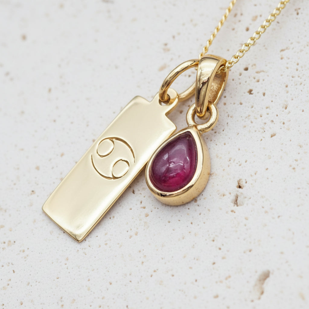 gold necklace with a gold cancer zodiac pendant and gold tear drop ruby gemstone pendant