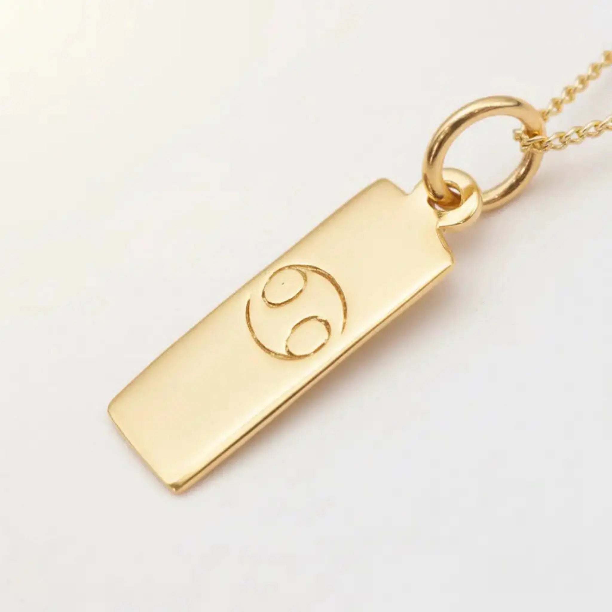 Minimalist Gold Cancer Zodiac pendant necklace on a white background