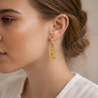 Gold earring worn by a person with a neutral background