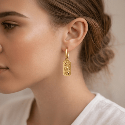 Gold earring worn by a person with a neutral background