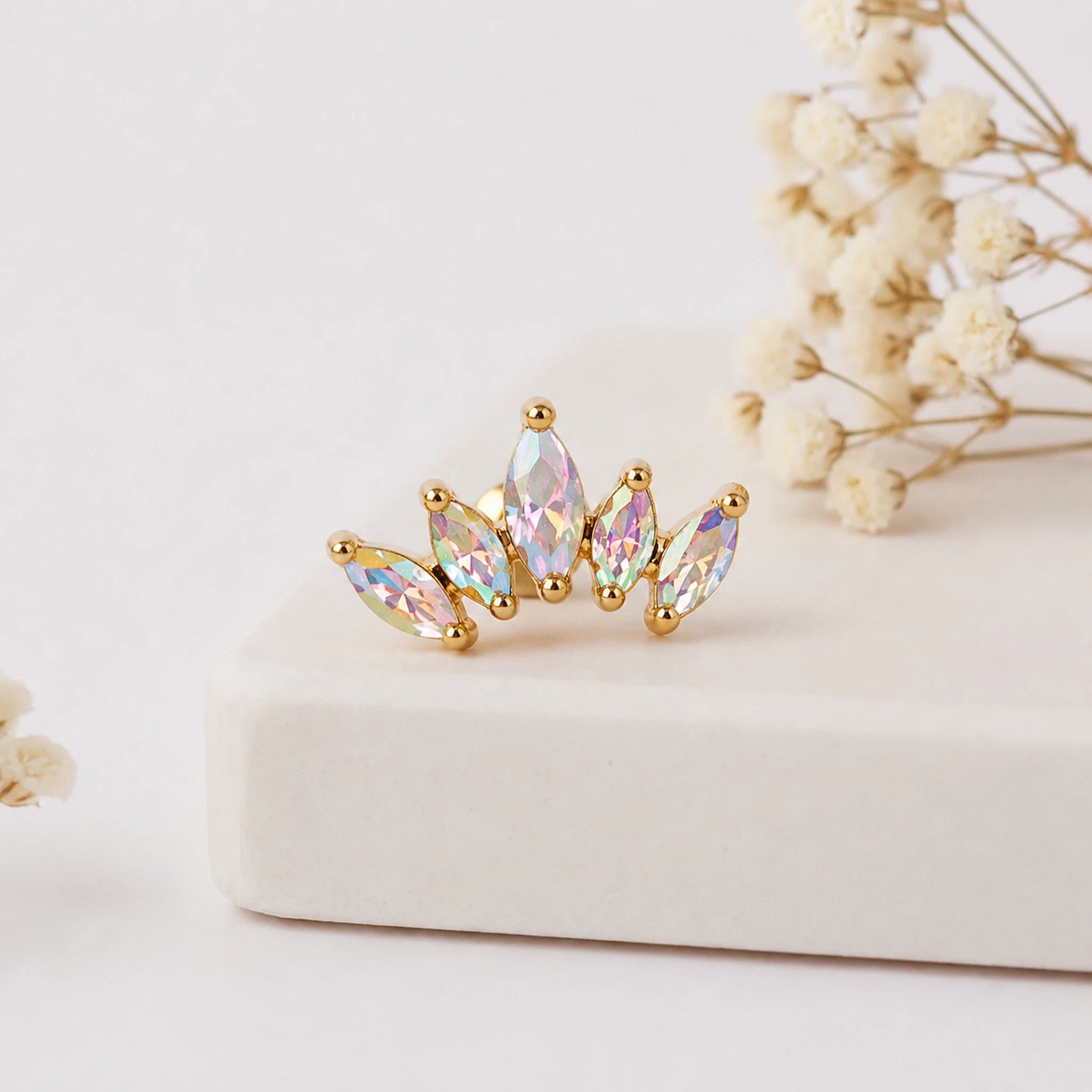Gold earring with colorful gemstones on a light background