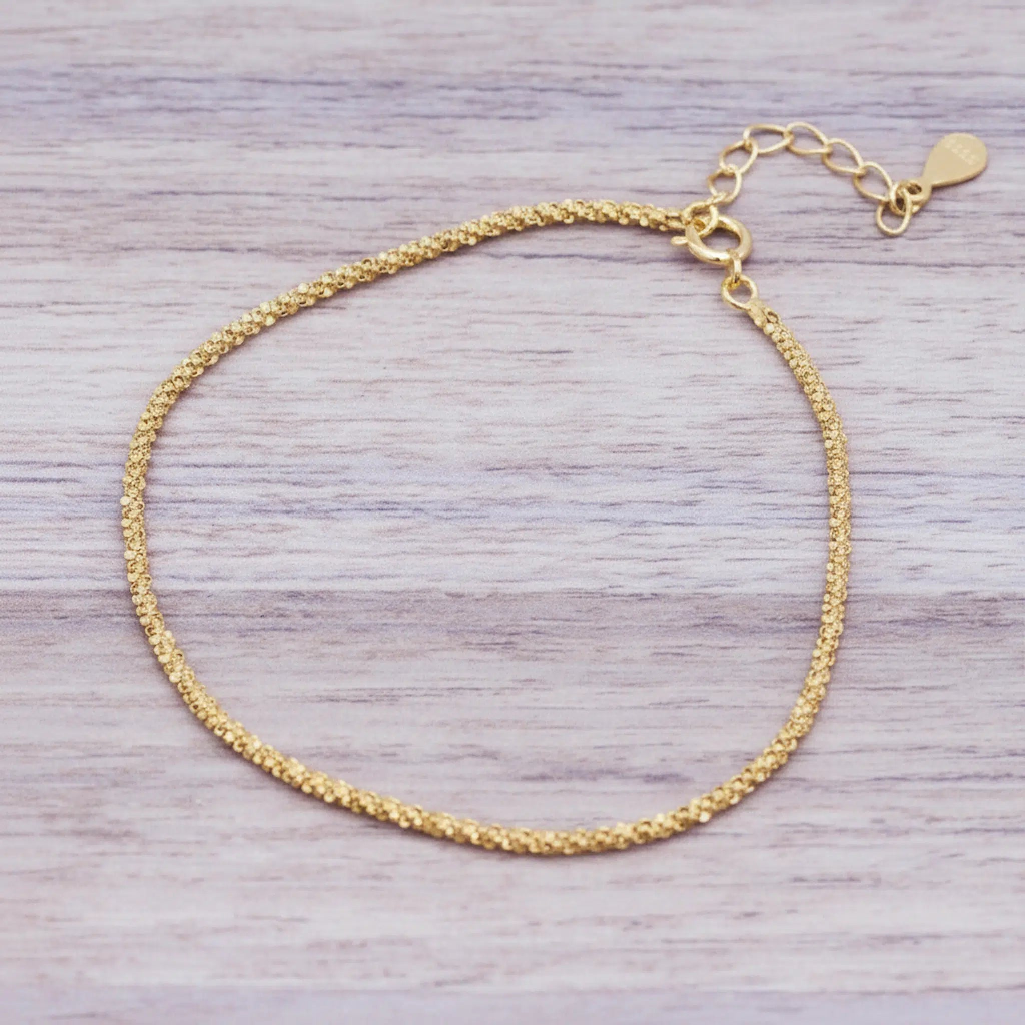 Gold bracelet on a light wooden surface