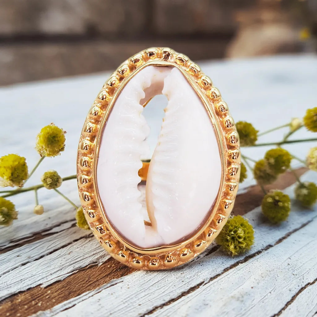 gold cowrie sea shell ring on a piece of rustic wood by indie and harper australia
