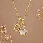 Gold initial D necklace with an April clear quartz teardrop on brown with dried flowers