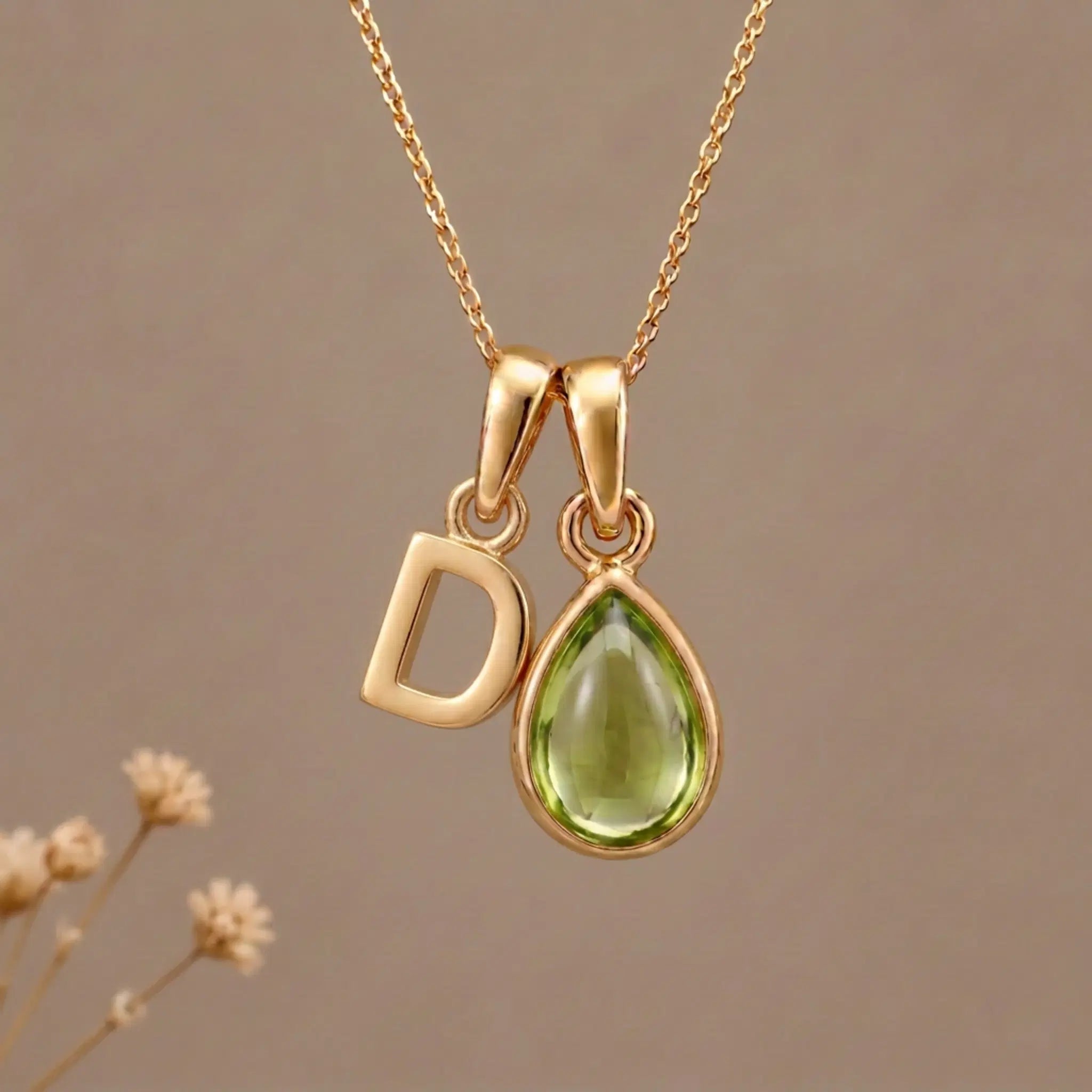 Gold Initial D Pendant and August birthstone Natural Peridot Necklace against a warm background